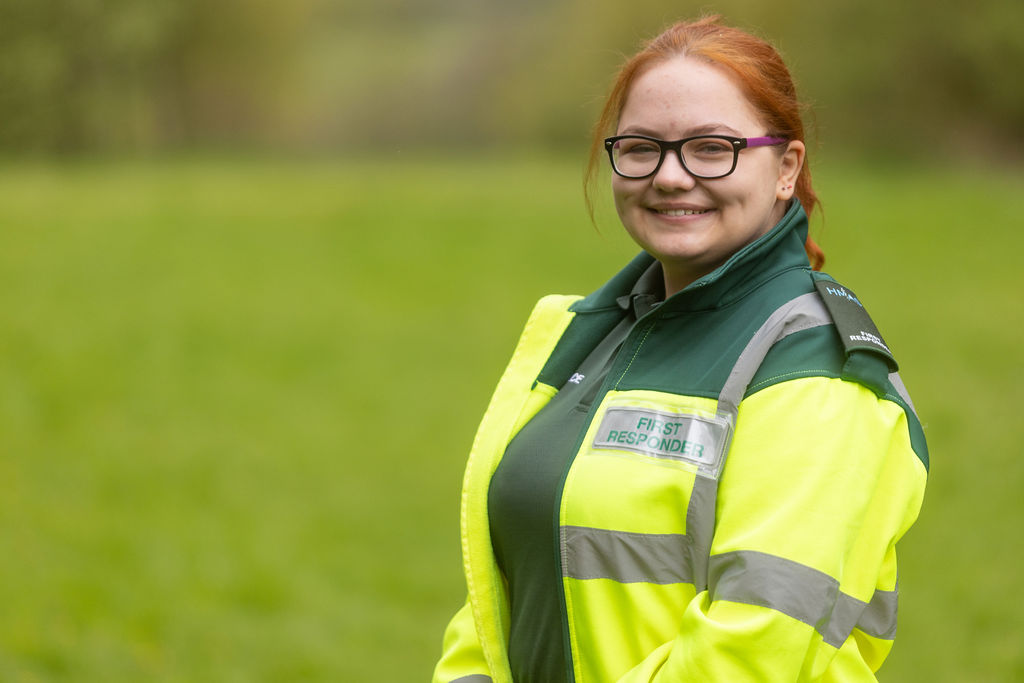 Anastasija Seglina, a young woman with red hair wearing yellow and green ambulance PPE.