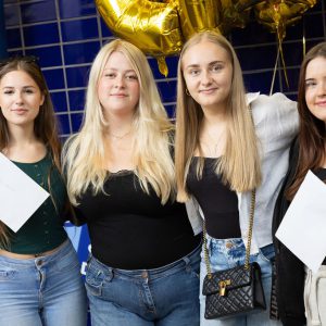 Four T Level Childcare students holding their result certificates.